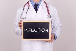 Doctor in a White Lab Coat Holding an Chalkboard That Says Infection